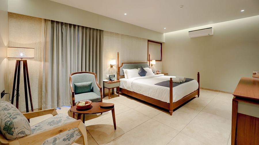 An image of villa featuring a king size bed, a chair, a bedside table, and a cabinet at Pride Resort Ambaji